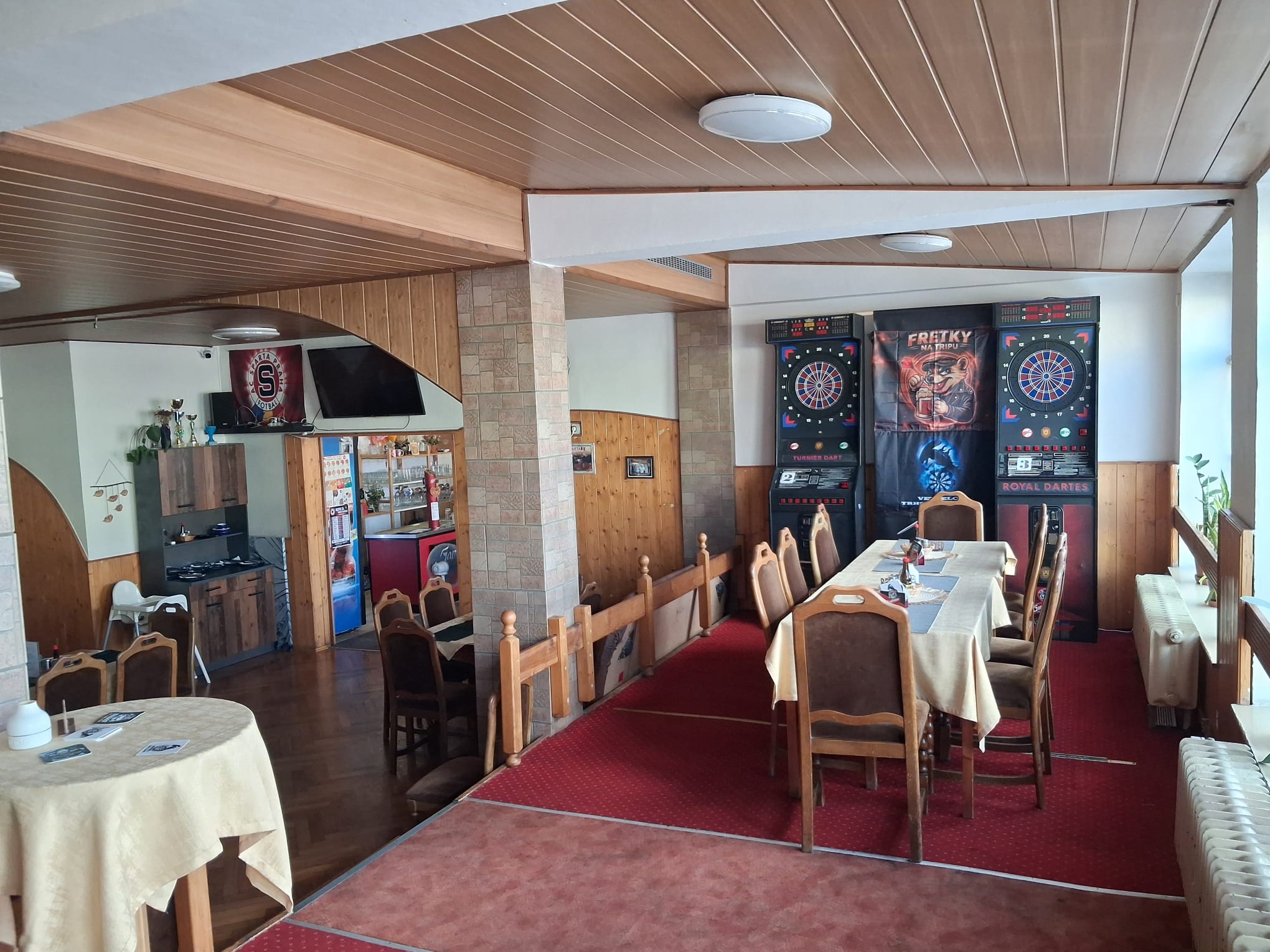 Vnitřní posezení restaurace s elektronickými šipkami a televizí